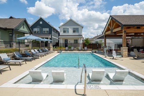 a swimming pool with chairs and umbrellas in front of houses